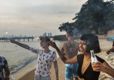 Group of diverse friends enjoying sparklers at the beach together stock images Group of diverse friends enjoying sparklers at the beach together stock images
