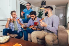 Four male friends drinking beer and eating pizza at home stock photo Four male friends drinking beer and eating pizza at home stock photo