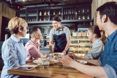 Group of friends looking at waiter serving food royalty free stock photo Group of friends looking at waiter serving food royalty free stock photo