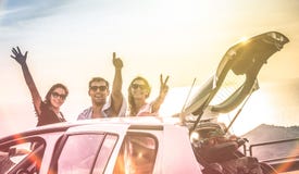 Group of happy best friends cheering on car road trip at sunset stock images Group of happy best friends cheering on car road trip at sunset stock images