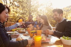 Group of happy friends eat and drink at a table at a barbecue stock photos Group of happy friends eat and drink at a table at a barbecue stock photos