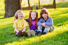 Group of happy little children smiling sitting in park on grass under a tree. royalty free stock image Group of happy little children smiling sitting in park on grass under a tree. royalty free stock image