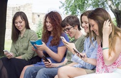 Group of happy young college students looking at mobile phones i stock image Group of happy young college students looking at mobile phones i stock image