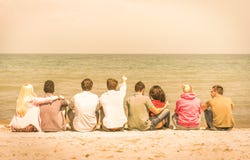 Group of international multiracial friends sitting at the beach