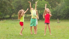 Group of kids play with soap bubbles in a park. Children active game. Slow motion