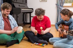 A group with a mentally disabled woman enjoys the music therapy
