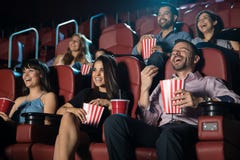 Group of people laughing at the movie theater. Small audience of people laughing at the movie theater while watching a comedy and having a good time Group of people laughing at the movie theater. Small audience of people laughing at the movie theater while watching a comedy and having a good time