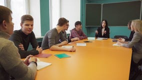 Group of students and a teacher sit at a table and talk