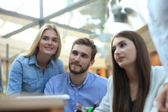 Group of young people in casual wear sitting at the office desk and discussing something while looking at PC together. stock image Group of young people in casual wear sitting at the office desk and discussing something while looking at PC together. stock image