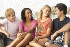Groupe d'adolescents s'asseyant dans la cour de jeu images libres de droits Groupe d'adolescents s'asseyant dans la cour de jeu images libres de droits