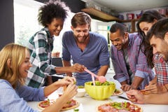 Groupe d'amis faisant la pizza dans la cuisine ensemble image stock Groupe d'amis faisant la pizza dans la cuisine ensemble image stock
