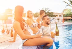 Groupe d'amis heureux faisant une réception au bord de la piscine au coucher du soleil - les jeunes riant et ayant le champagne p image stock Groupe d'amis heureux faisant une réception au bord de la piscine au coucher du soleil - les jeunes riant et ayant le champagne p image stock