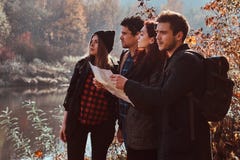 Groupe de jeunes amis trimardant dans la forêt colorée d'automne, regardant la carte et prévoyant la hausse photo libre de droits Groupe de jeunes amis trimardant dans la forêt colorée d'automne, regardant la carte et prévoyant la hausse photo libre de droits