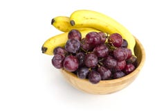 Groupes juteux d'isolement de grands raisins rouges et de bananes mûres dans une cuvette en bois images stock Groupes juteux d'isolement de grands raisins rouges et de bananes mûres dans une cuvette en bois images stock