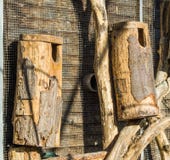 Große handgefertigte leere hölzerne Vogelhäuser machten von einem Baumstamm und -holz, die auf der Wand hängen stockfotografie Große handgefertigte leere hölzerne Vogelhäuser machten von einem Baumstamm und -holz, die auf der Wand hängen stockfotografie