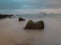 Großer Felsen auf einem spanischen Strand mit einer Insel auf dem Hintergrund lizenzfreie stockfotos Großer Felsen auf einem spanischen Strand mit einer Insel auf dem Hintergrund lizenzfreie stockfotos
