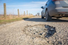 Großes Schlagloch auf einer Landstraße mit dem Führen des Autos lizenzfreie stockfotos Großes Schlagloch auf einer Landstraße mit dem Führen des Autos lizenzfreie stockfotos