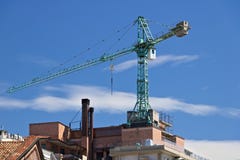 Gru di costruzione montata sul tetto di una costruzione a Milano fotografia stock Gru di costruzione montata sul tetto di una costruzione a Milano fotografia stock