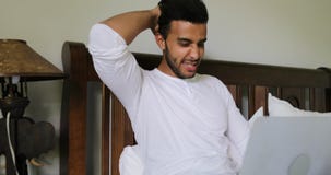Grubbla mannen som använder sammanträde för bärbar datordator på morgon för sänglatinamerikanGuy Type Chatting Online In sovrum lager videofilmer Grubbla mannen som använder sammanträde för bärbar datordator på morgon för sänglatinamerikanGuy Type Chatting Online In sovrum lager videofilmer