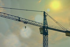 Grue fonctionnant dans le secteur de construction avec la fusée du soleil photo libre de droits Grue fonctionnant dans le secteur de construction avec la fusée du soleil photo libre de droits