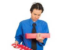 Grumpy man opening gift box looking upset displeased at what he received stock photography Grumpy man opening gift box looking upset displeased at what he received stock photography