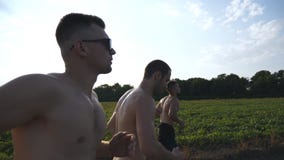 Grupa młodzi człowiecy biega wzdłuż wiejskiej drogi nad polem z słońce racą przy tłem Profil męskie atlety jogging wewnątrz fotografia stock Grupa młodzi człowiecy biega wzdłuż wiejskiej drogi nad polem z słońce racą przy tłem Profil męskie atlety jogging wewnątrz fotografia stock