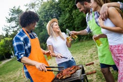 Grupo de amigos felizes que comem e que bebem cervejas no jantar do assado imagem de stock royalty free Grupo de amigos felizes que comem e que bebem cervejas no jantar do assado imagem de stock royalty free