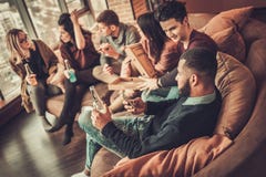 Grupo de amigos jovenes étnicos multi que comen la pizza en el interior casero foto de archivo libre de regalías Grupo de amigos jovenes étnicos multi que comen la pizza en el interior casero foto de archivo libre de regalías
