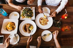 Grupo de amigos masculinos y femeninos que cenan y que comen el filete y ensalada y espaguetis juntos en el restaurante - visión imagen de archivo Grupo de amigos masculinos y femeninos que cenan y que comen el filete y ensalada y espaguetis juntos en el restaurante - visión imagen de archivo