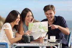 Grupo de amigos novos do turista que consultam um mapa de papel imagem de stock royalty free Grupo de amigos novos do turista que consultam um mapa de papel imagem de stock royalty free