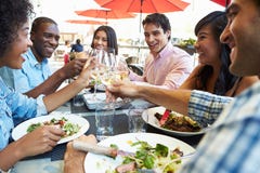 Grupo de amigos que apreciam a refeição no restaurante exterior