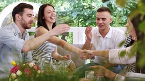 Grupo de amigos que hacen apostado sacudiendo las manos en la reunión en café Grupo de amigos que hacen apostado sacudiendo las manos en la reunión en café