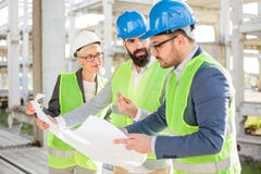 Grupo de arquitetos ou de sócios comerciais que têm a reunião sobre um canteiro de obras imagem de stock Grupo de arquitetos ou de sócios comerciais que têm a reunião sobre um canteiro de obras imagem de stock
