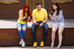 Grupo de juventud que juega al videojuego móvil al aire libre fotos de archivo libres de regalías Grupo de juventud que juega al videojuego móvil al aire libre fotos de archivo libres de regalías
