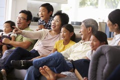 Grupo de la familia extensa en casa que ve la TV junto fotografía de archivo libre de regalías Grupo de la familia extensa en casa que ve la TV junto fotografía de archivo libre de regalías