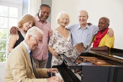Grupo de mayores que hacen una pausa el piano y que cantan junto fotografía de archivo Grupo de mayores que hacen una pausa el piano y que cantan junto fotografía de archivo