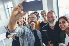 Grupo de personas multirracial que toma el selfie en la oficina fotografía de archivo Grupo de personas multirracial que toma el selfie en la oficina fotografía de archivo
