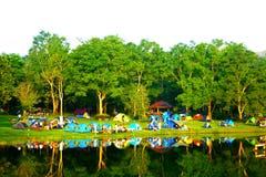 Grupo de tienda de campaña de la gente de la felicidad con el pequeño bosque y el lago foto de archivo Grupo de tienda de campaña de la gente de la felicidad con el pequeño bosque y el lago foto de archivo