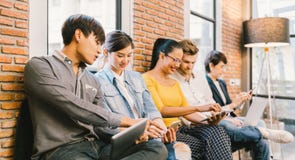 Grupo diverso multiétnico de gente joven y adulta que usa el smartphone, ordenador portátil, tableta digital junto fotografía de archivo Grupo diverso multiétnico de gente joven y adulta que usa el smartphone, ordenador portátil, tableta digital junto fotografía de archivo
