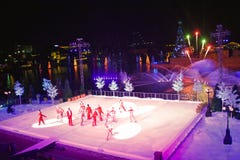 Grupo do artista que patina na mostra do Natal no gelo no fundo colorido com os fogos de artifício na área internacional da movim fotografia de stock Grupo do artista que patina na mostra do Natal no gelo no fundo colorido com os fogos de artifício na área internacional da movim fotografia de stock