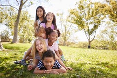 grupo Multi-étnico de niños que mienten en una pila en un parque imagenes de archivo grupo Multi-étnico de niños que mienten en una pila en un parque imagenes de archivo