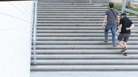 Grupp människor på den tillbaka sidan går upp det yttre konkreta trappalandskapet arkivbild Grupp människor på den tillbaka sidan går upp det yttre konkreta trappalandskapet arkivbild