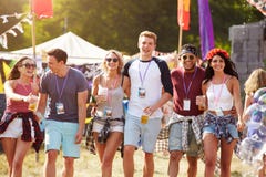 Gruppe Freunde, die durch einen Musikfestivalstandort gehen lizenzfreies stockbild Gruppe Freunde, die durch einen Musikfestivalstandort gehen lizenzfreies stockbild