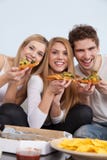 Gruppe junge Leute, die zu Hause Pizza essen lizenzfreie stockfotos Gruppe junge Leute, die zu Hause Pizza essen lizenzfreie stockfotos