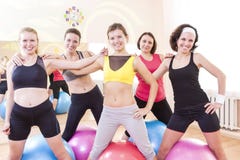 Gruppe von fünf glücklichen kaukasischen weiblichen Athleten, die zusammen umfasst gegen Fitballs aufwerfen lizenzfreies stockfoto Gruppe von fünf glücklichen kaukasischen weiblichen Athleten, die zusammen umfasst gegen Fitballs aufwerfen lizenzfreies stockfoto