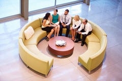 Gruppe Wirtschaftler, die Sitzung in der Büro-Lobby haben lizenzfreie stockfotos Gruppe Wirtschaftler, die Sitzung in der Büro-Lobby haben lizenzfreie stockfotos