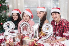 Gruppo di amici che celebrano il Natale a casa e che mostrano 2019 fotografie stock libere da diritti Gruppo di amici che celebrano il Natale a casa e che mostrano 2019 fotografie stock libere da diritti