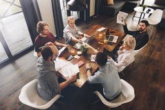 Gruppo di gente coworking che si siede intorno alla tavola e al workin di legno fotografia stock Gruppo di gente coworking che si siede intorno alla tavola e al workin di legno fotografia stock