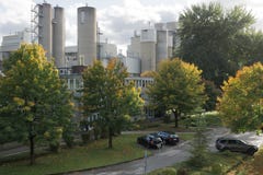 Grå fabrik med gröna träd och parkering arkivfoton Grå fabrik med gröna träd och parkering arkivfoton
