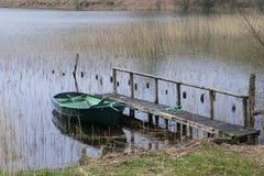 Grön eka som binds med repet till träbryggapir i sjöfjorden inom Argyll Skottland royaltyfri foto Grön eka som binds med repet till träbryggapir i sjöfjorden inom Argyll Skottland royaltyfri foto